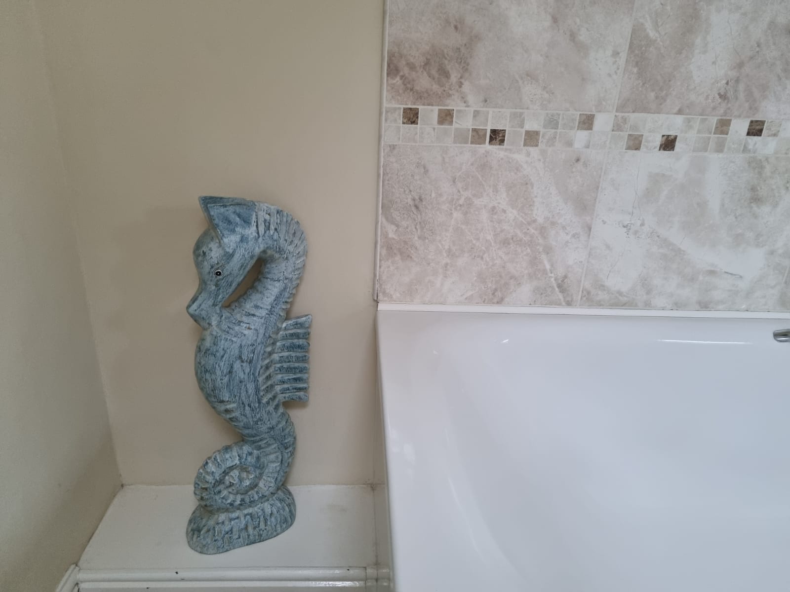 statue of a seahorse next to the bathtub in the bathroom of Granary cottage